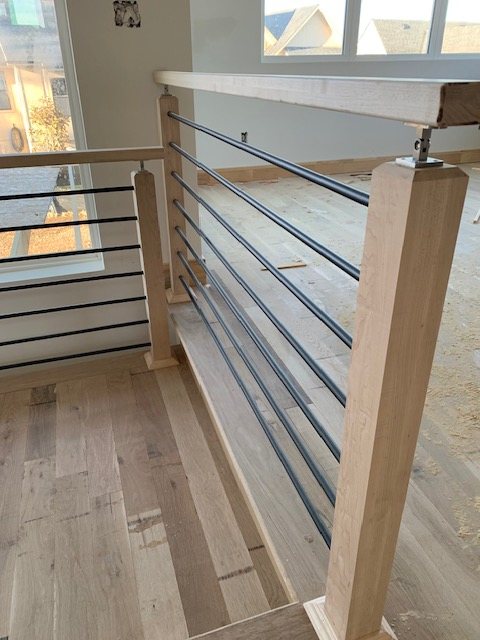 Close detail of an oak handrail post with horizontal metal rails