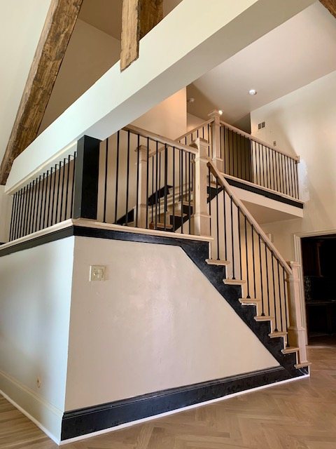 Staircase with black iron balusters, oak handrail and boxed newel posts
